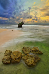 Close-up of rock on beach against sky during sunset