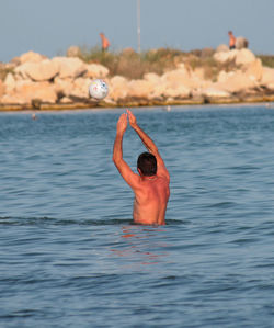 Shirtless man in sea against sky