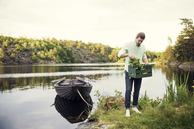 Full length of man carrying vegetables crate while standing at lakeshore