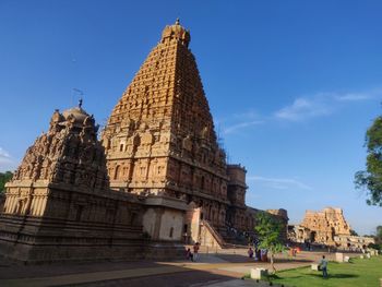 People outside temple against blue sky