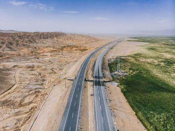 Aerial view of roads amidst field and arid landscape against sky