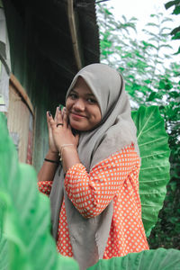 Portrait of smiling woman standing against plants