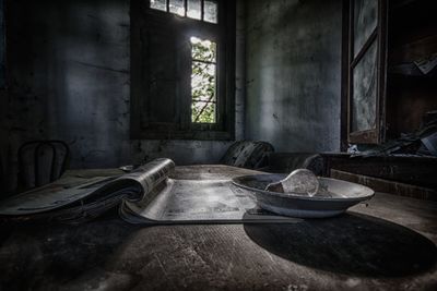 Paper and bowl on table of abandoned building