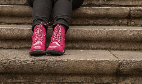 Low section of woman wearing boots sitting on steps