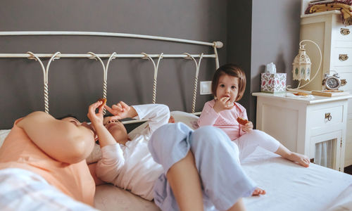 Cheerful mother playing with son and daughter while lying bed at home