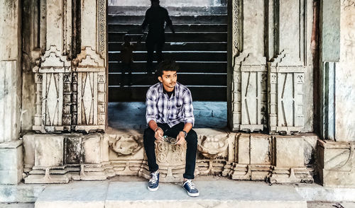 Full length portrait of young man standing against entrance