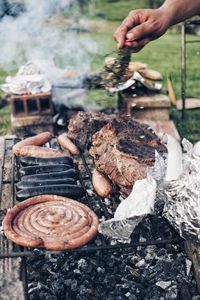 Midsection of person preparing food on barbecue grill