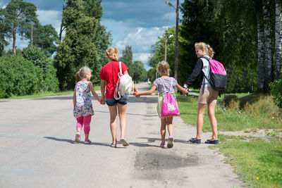 Rear view of children walking on road