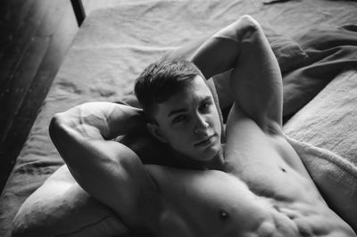 High angle portrait of shirtless man lying on bed at home