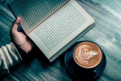  man read a book when he was drinking a cup of coffee.