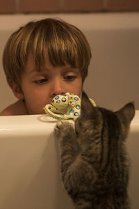 Boy with cat and toy in bathtub at home