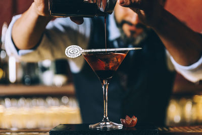 Bartender preparing cocktail at counter in bar