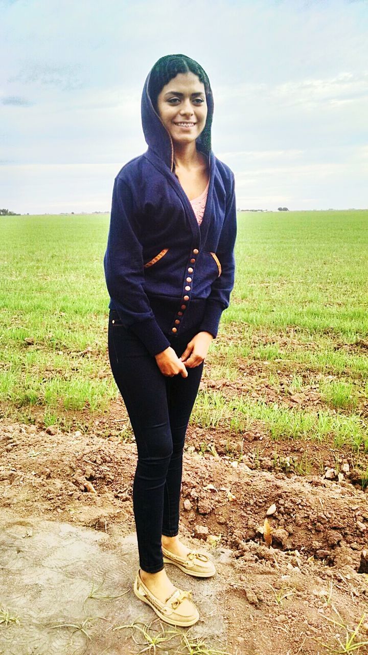 portrait, person, looking at camera, young adult, casual clothing, sky, lifestyles, front view, leisure activity, standing, smiling, full length, field, grass, landscape, young women, cloud - sky