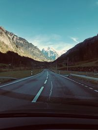 Road amidst mountains seen through car windshield