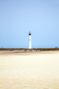 Lighthouse on beach against sky