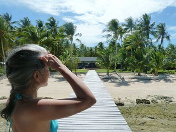 Young woman with palm trees on beach against sky