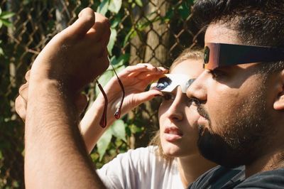 Friends looking at eyeglasses while wearing 3-d glasses during sunny day