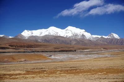 Scenic view of snowcapped mountains against blue sky