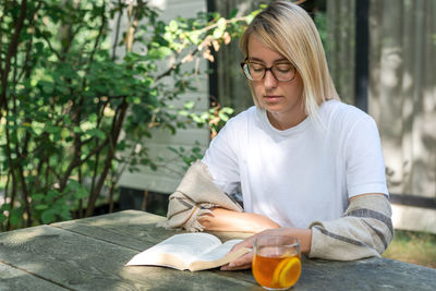 Mid adult woman reading book outdoors