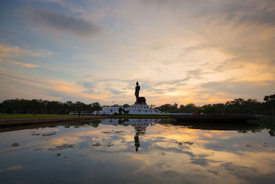 Statue in lake during sunset