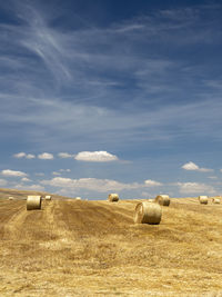 Hay bales on field against sky