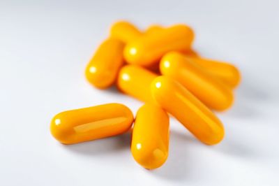 Orange vitamin pills on white surface