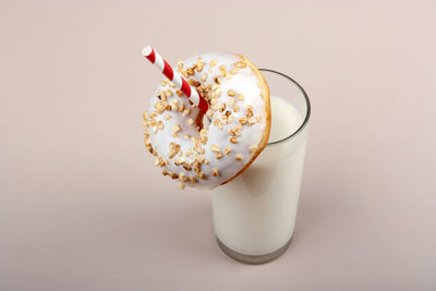 Glass of milk and donut on pink background