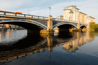 Bridge over river in city against sky