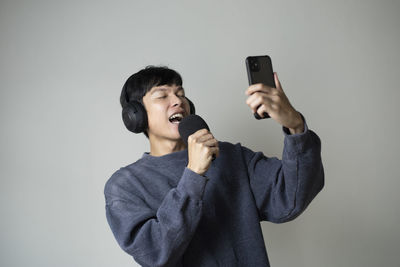 Young man using smart phone against white background