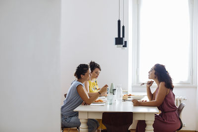 Content women chatting while enjoying dinner at home