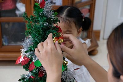 Mother and daughter decorating christmas tree at home