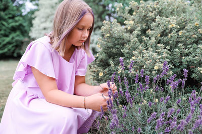 Side view of young woman standing amidst plants