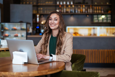 Young woman using phone while sitting on table