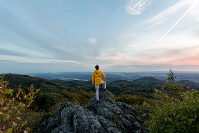 Rear view of man standing on rock against sky