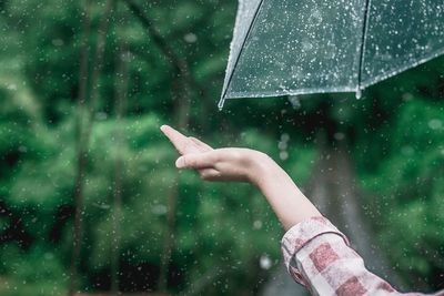 Hand holding wet glass during rainy season