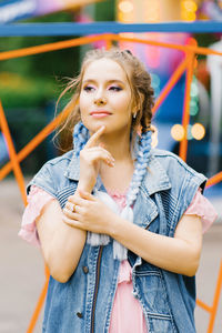 Stylish young woman with blue pigtails walks in an amusement park