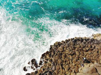 High angle view of rocks on shore at beach by sea