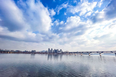 Bridge over river against cloudy sky