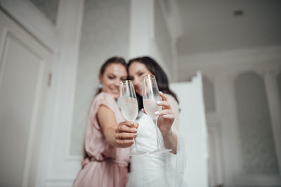 Bridesmaid and bride holding champagne flute