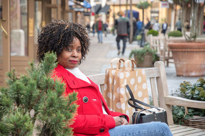 An african woman with big shopping bags relaxing after shopping on outdoor bench