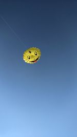 Low angle view of yellow butterfly against clear blue sky