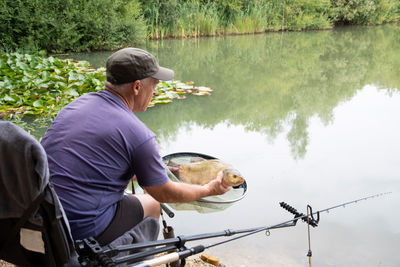 The fisherman caught a bream with a net for a successful catch in the summer on the lake, fishing