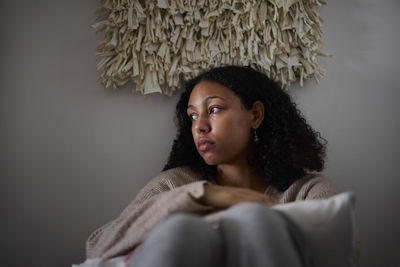 Pensive young woman sitting at home