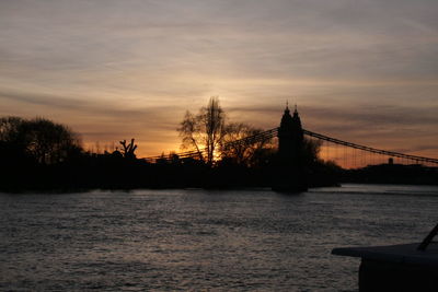 Silhouette of bridge over river during sunset