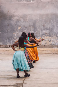 Rear view of women standing against wall