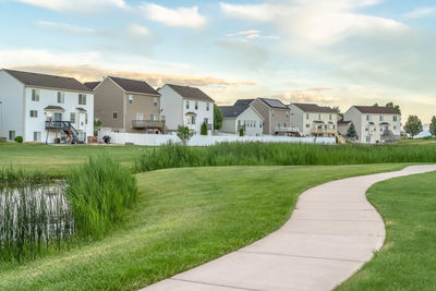 Houses on field by buildings against sky