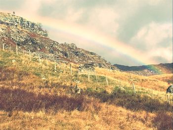 Scenic view of field against rainbow in sky