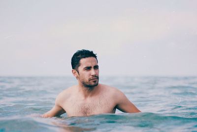 Young man looking at sea against sky