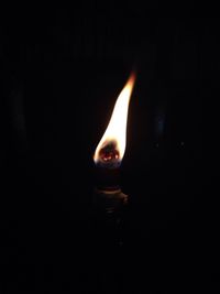 Close-up of burning candle in darkroom