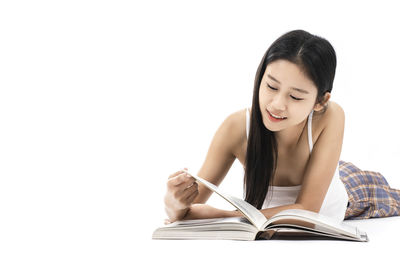 Young woman reading book against white background